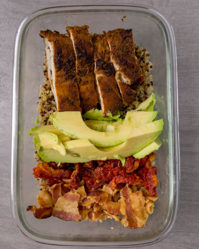 Roasted Turkey, sliced avocado, chopped sundried tomatoes, crumbled bacon over a bed of quinoa in a glass container. 