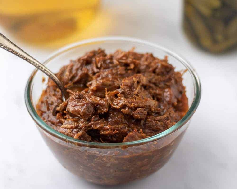 Shredded BBQ pulled pork in a glass bowl.