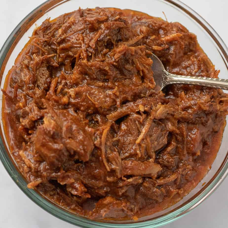 Shredded BBQ pulled pork in a glass bowl.