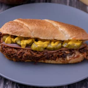 BBQ pulled pork cuban sandwich on a blue plate.