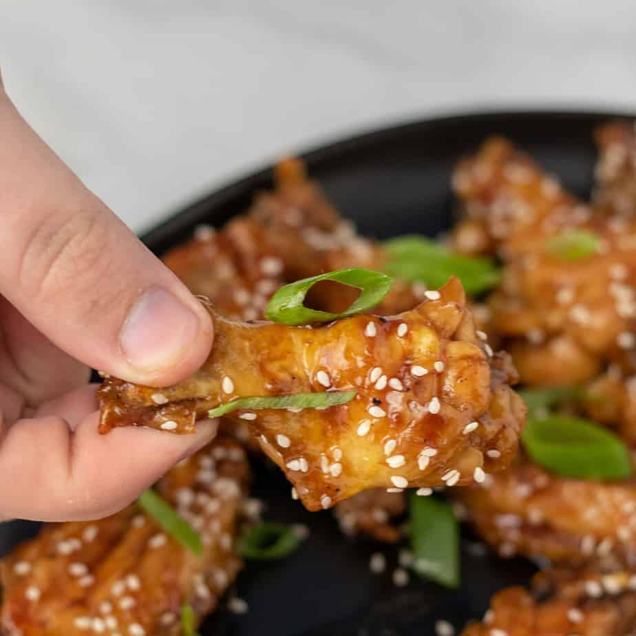 Chicken wing covered in teriyaki sauce, scallions and sesame seeds