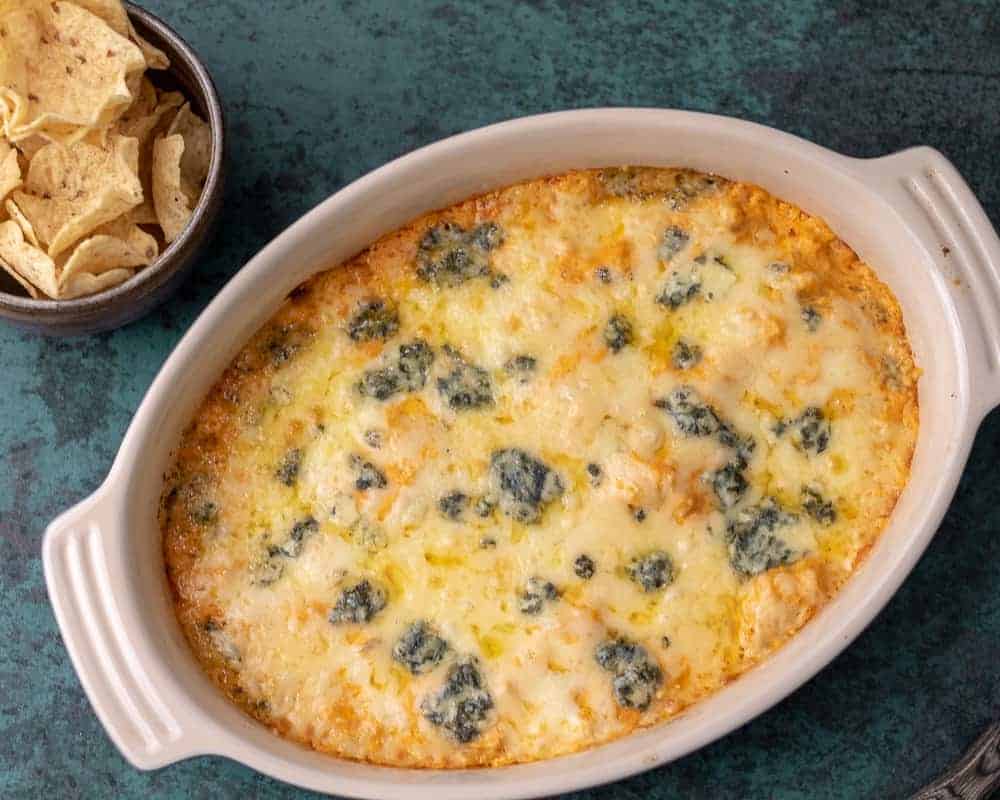 Buffalo chicken dip in a ceramic dish with chips on the side.