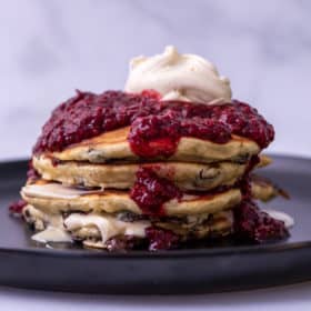 Side view of pancakes with mascarpone, chocolate chips and raspberries