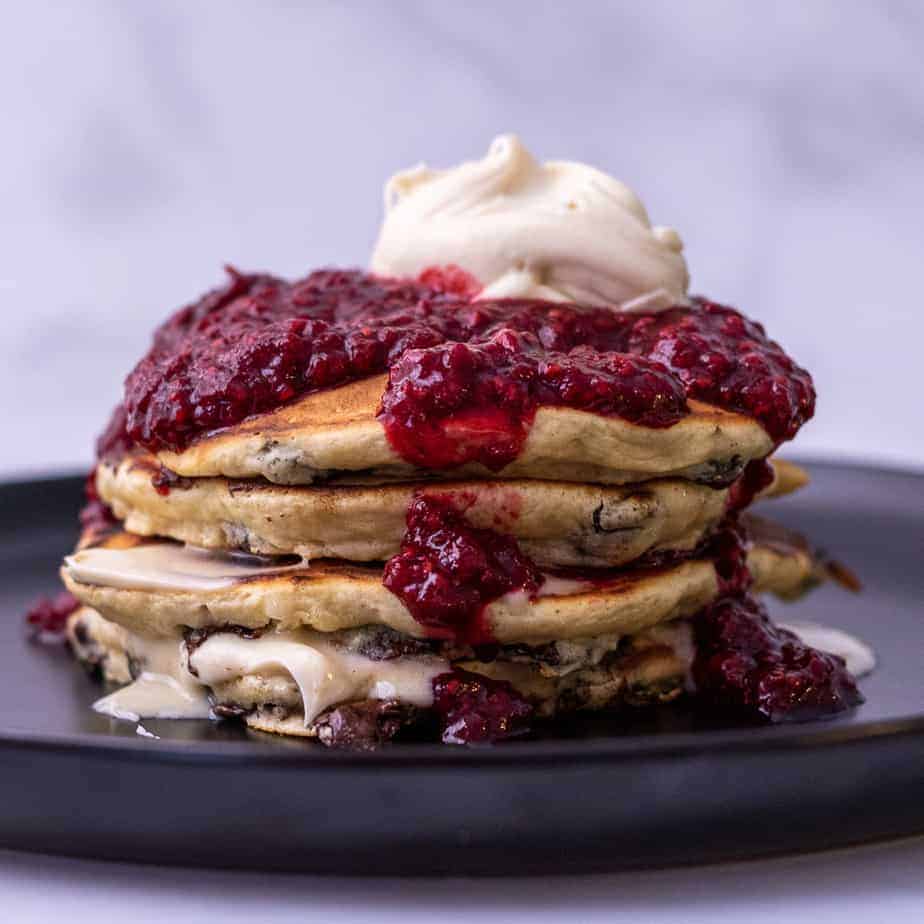 Side view of pancakes with mascarpone, chocolate chips and raspberries
