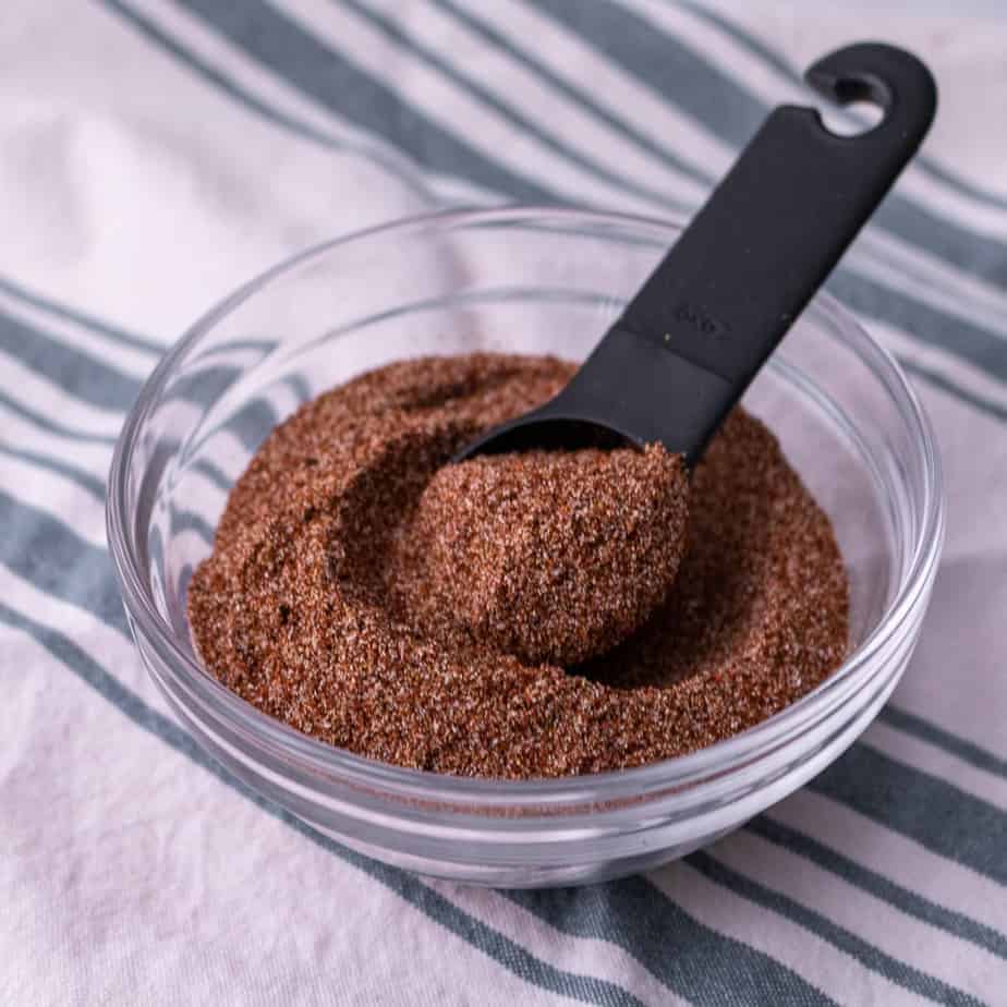 A bowl of taco seasoning with a black measuring spoon