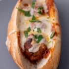 One meatball sub with melted cheese and parsley