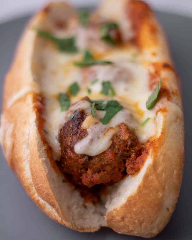 One meatball sub with melted cheese and parsley