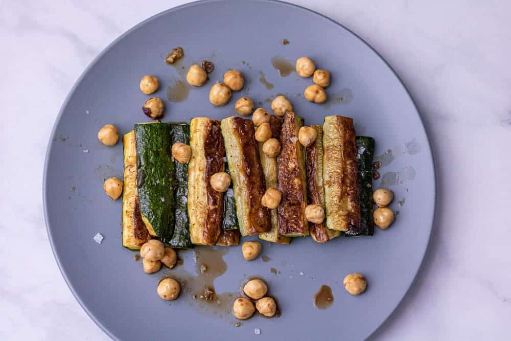 Roasted zucchini with balsamic and halzenuts on a blue plate