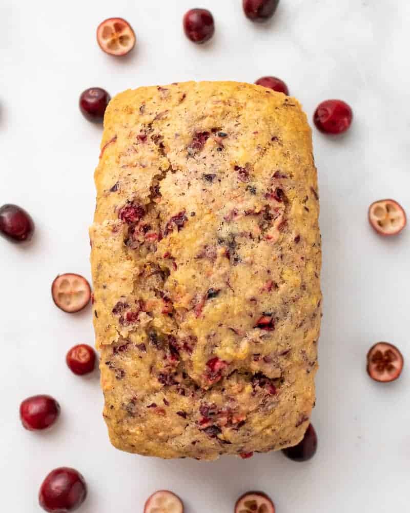 close up of a mini loaf with fresh cranberries scattered around