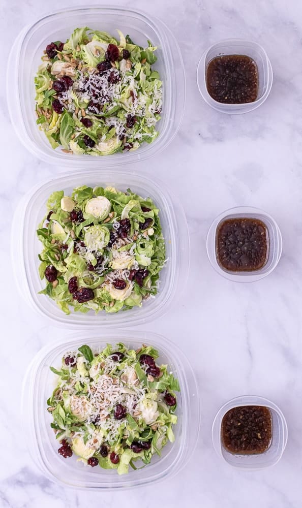 3 bowls of Shredded brussel sprouts with dressing on the side.