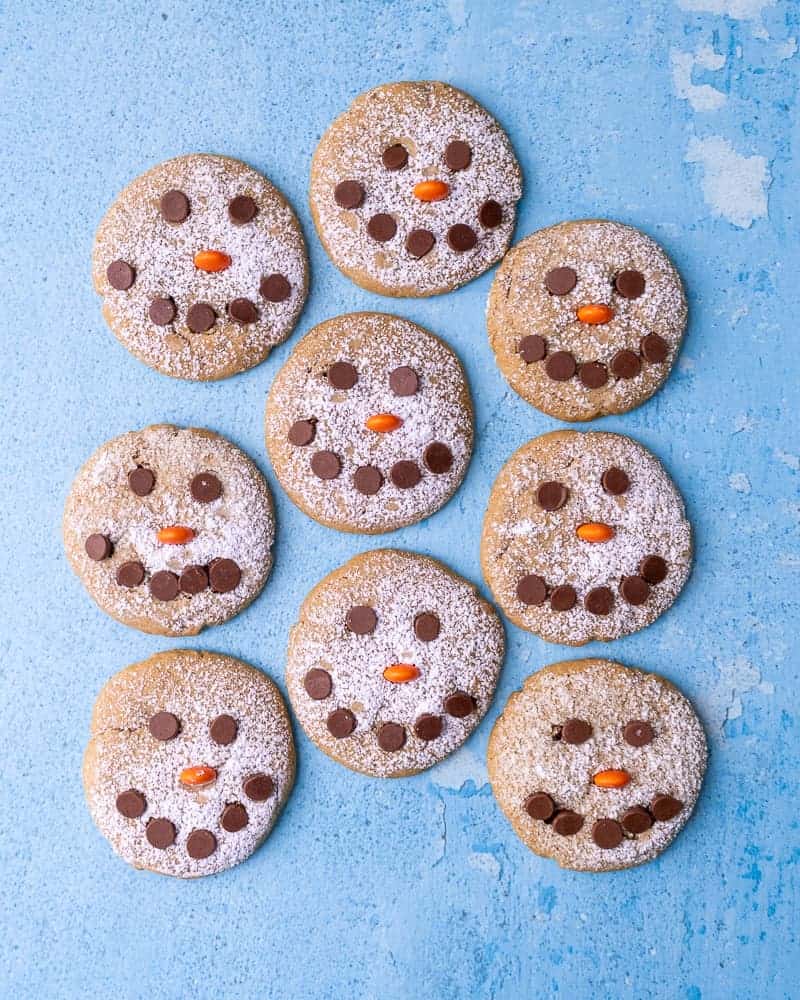 9 Snowman cookies in a cluster on a blue background