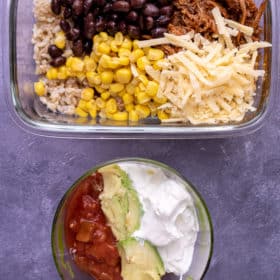 A final photo of the pork burrito bowl base next to a separate container of sour cream, avocado and salsa.