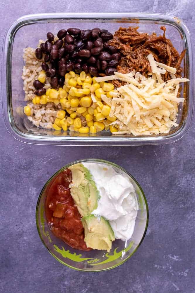 A final photo of the pork burrito bowl base next to a separate container of sour cream, avocado and salsa.