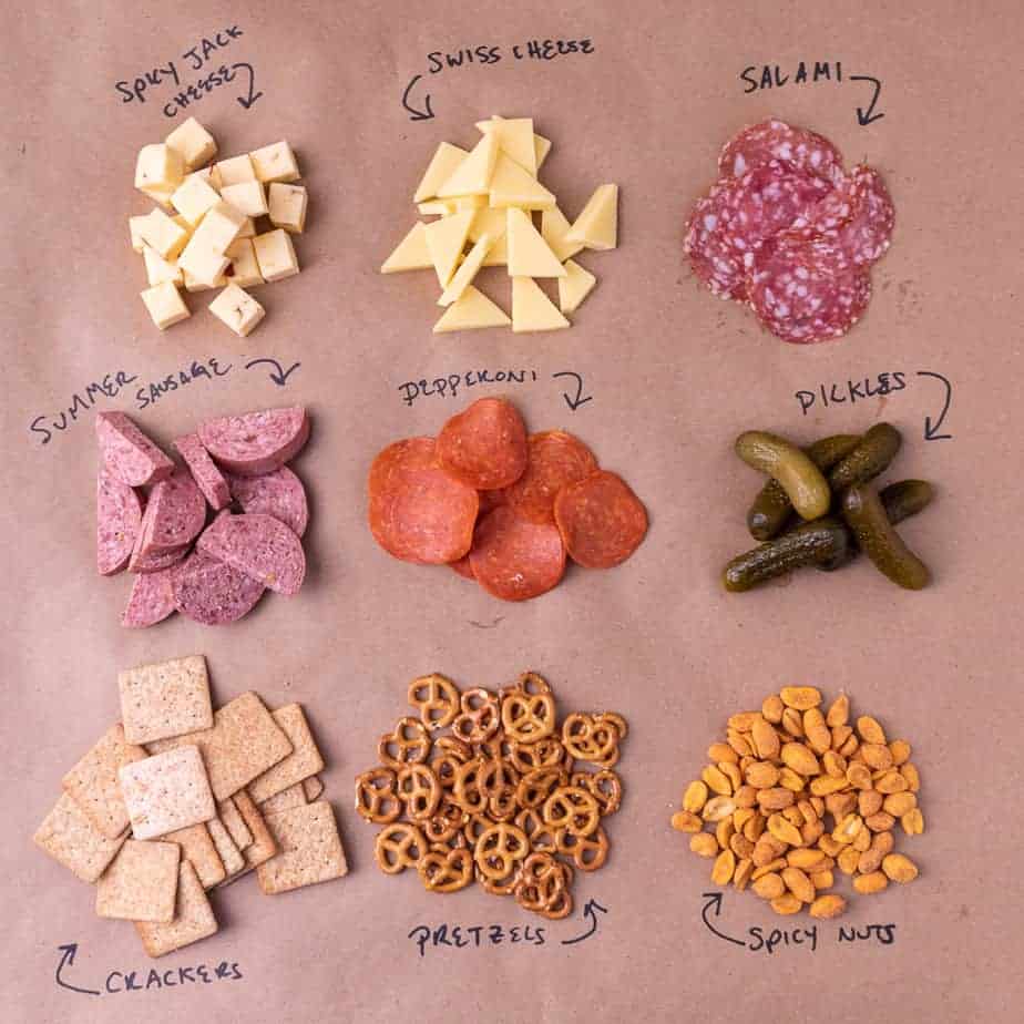 All 9 ingredients of the Super Bowl cheese board laid out and labeled on brown paper