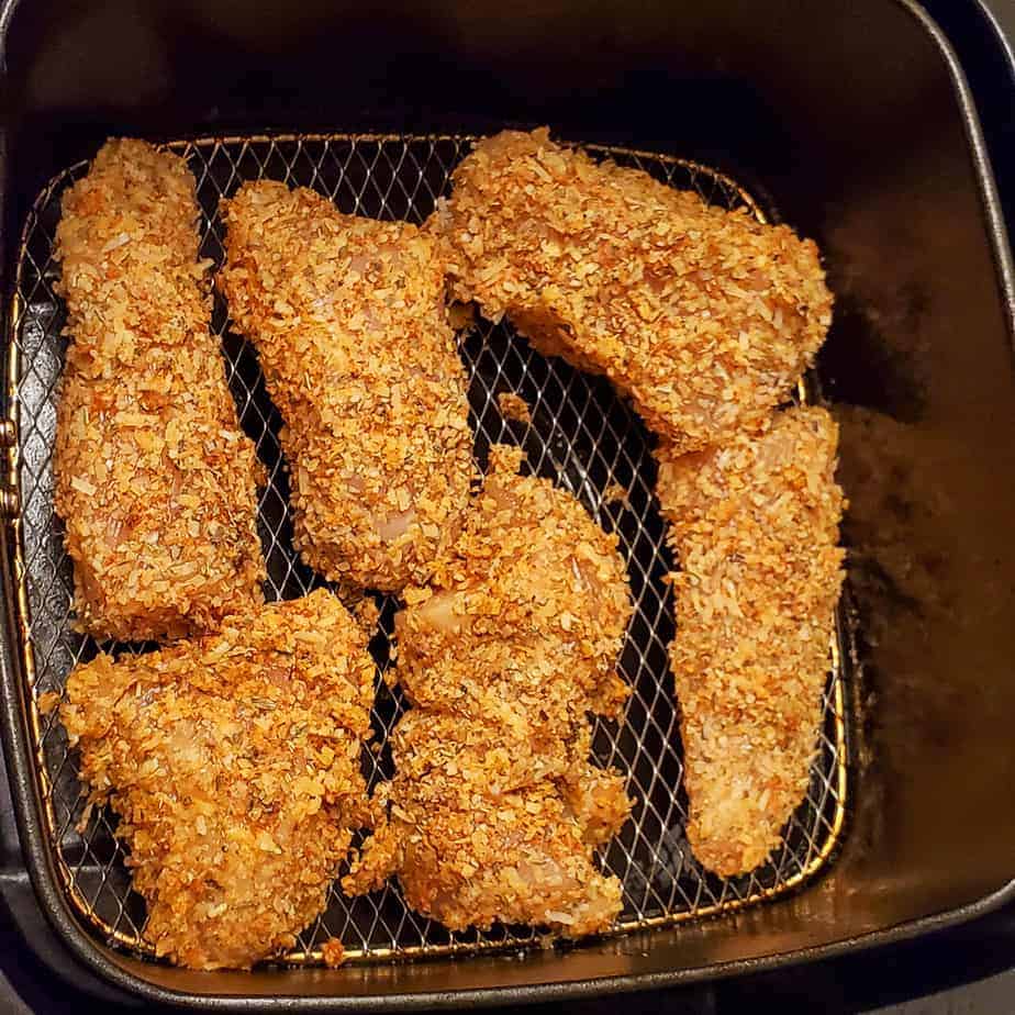 Raw parmesan crusted chicken in the air fryer basket.