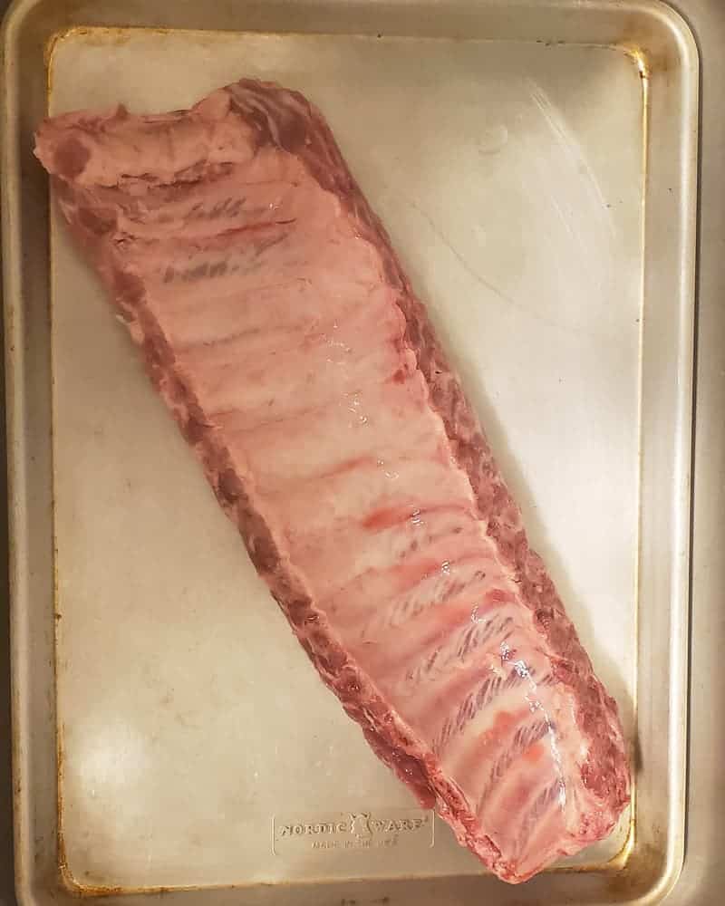 A whole rack of ribs on a sheet tray