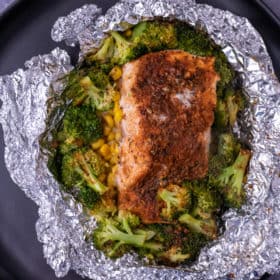 Close up of cooked cajun salmon in foil with veggies.