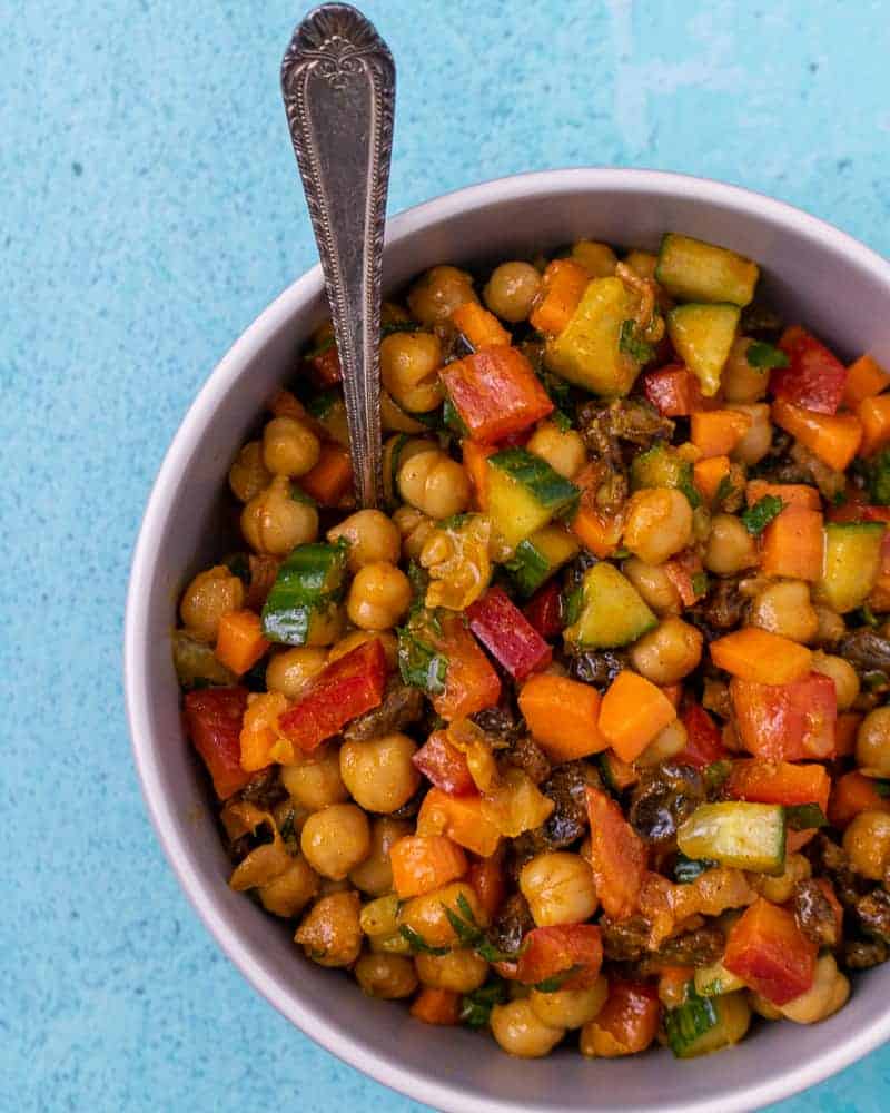 Overhead Shot of chickpea salad with a spoon on a blue background