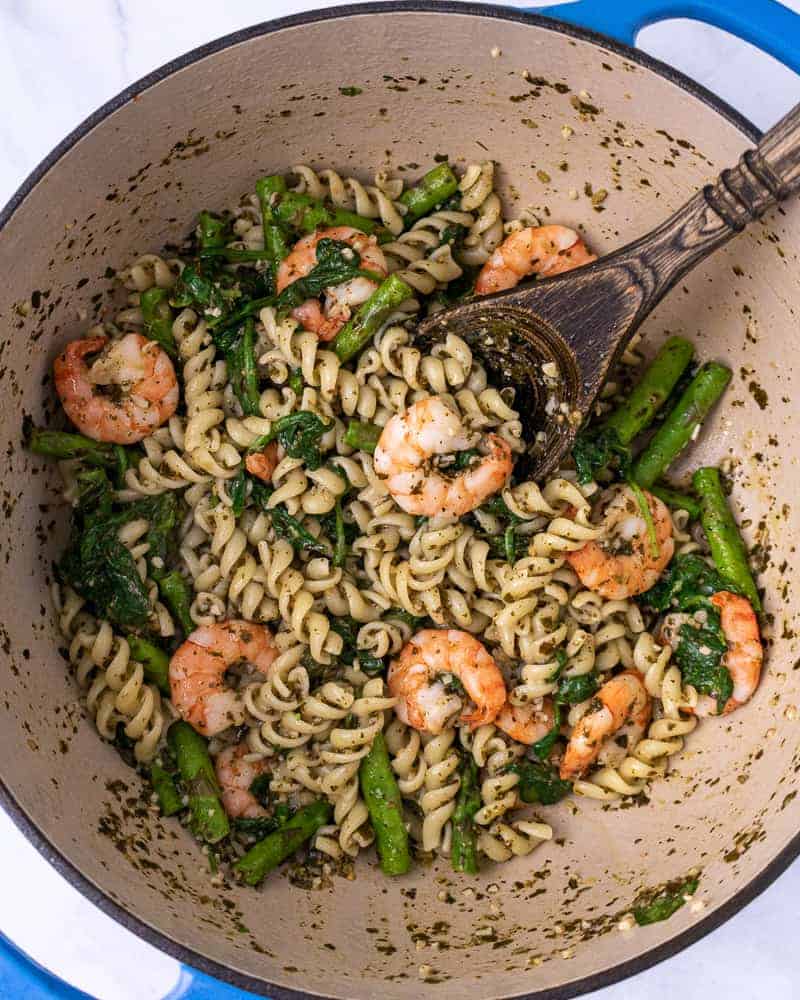 Lemon pesto pasta with shrimp mixed up in a dutch oven.