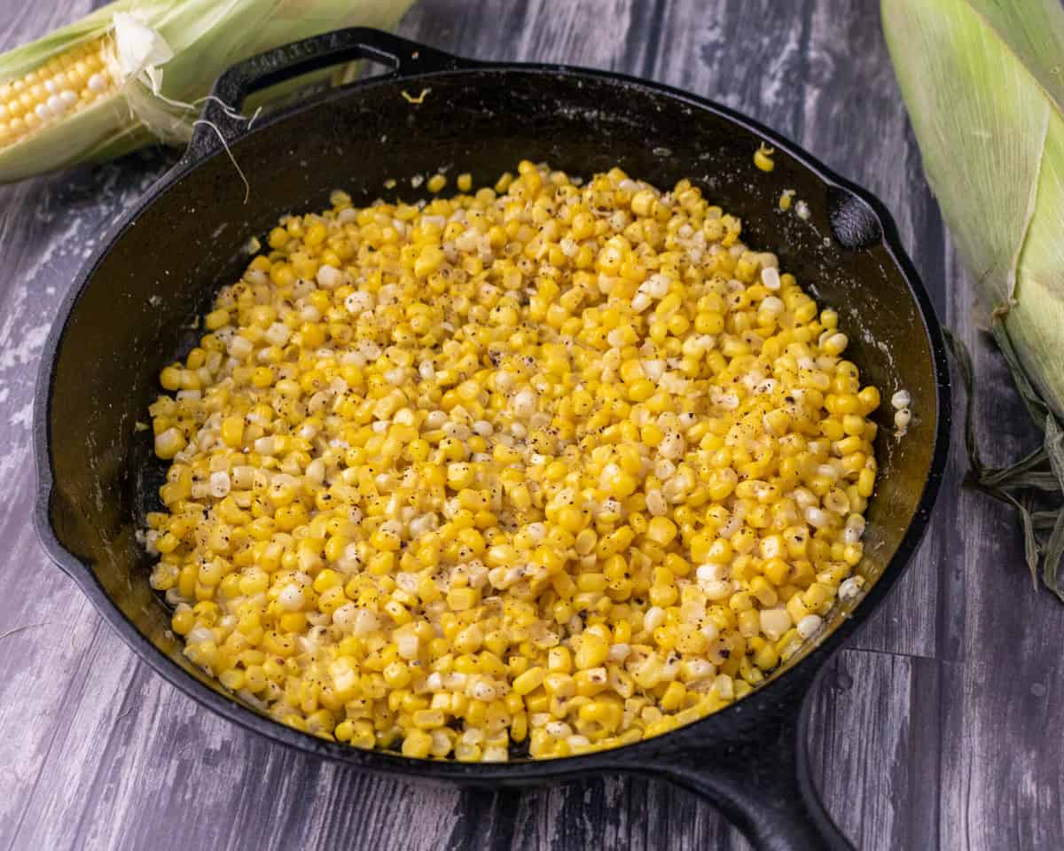 Miso butter corn in a cast iron skillet with corn on the cob in the background