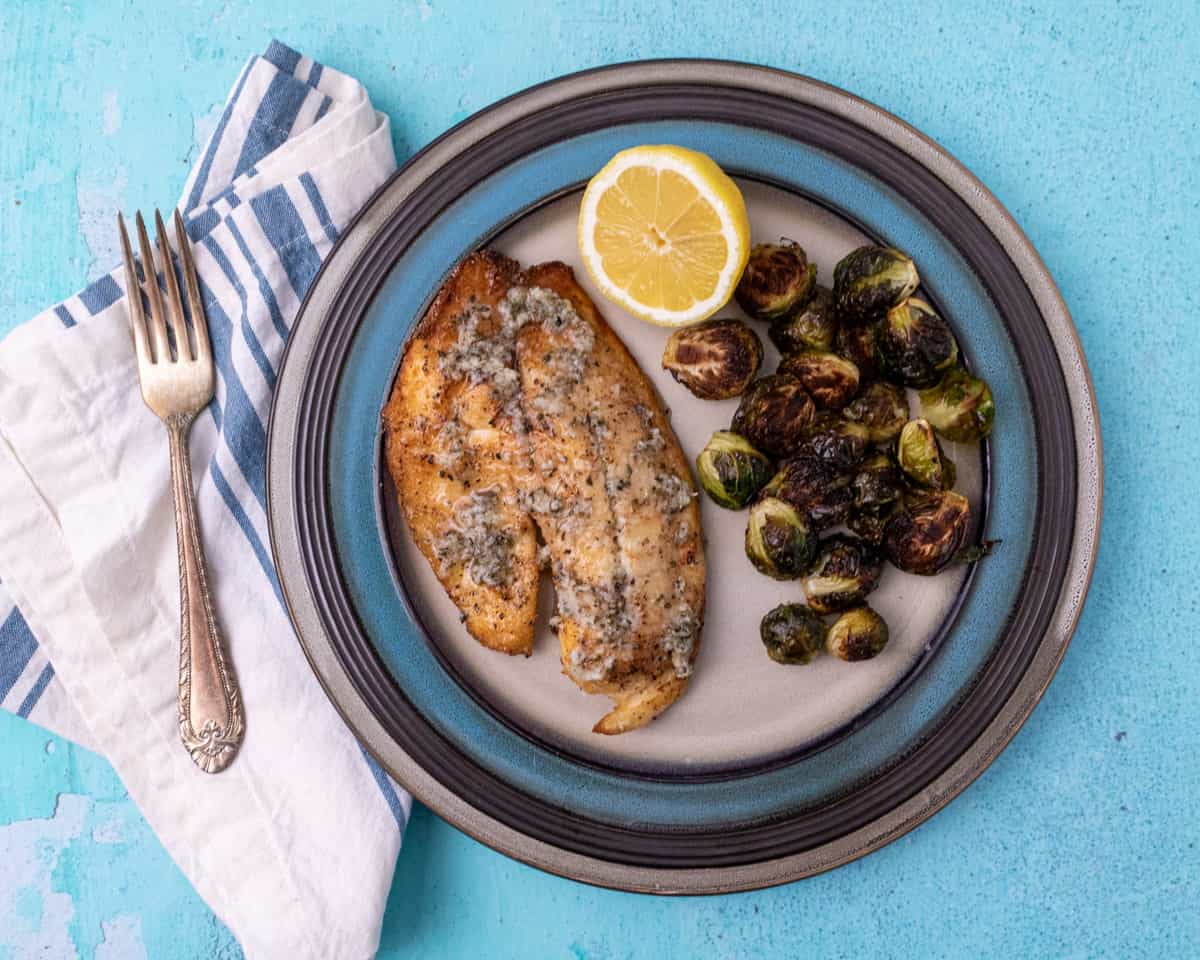 Close up of cooked tilapia with a fresh cut lemon