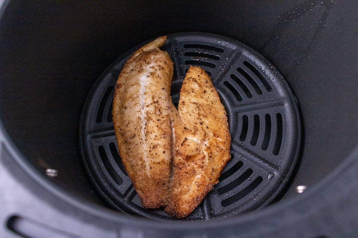 Cooked piece of tilapia in the air fryer basket