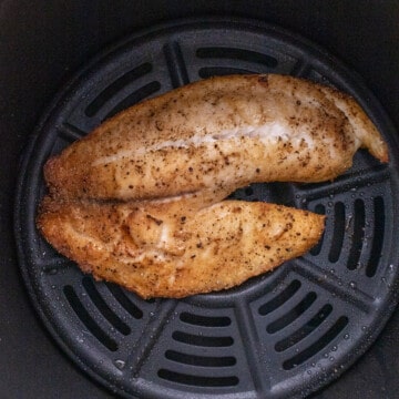 Cooked piece of tilapia in the air fryer basket