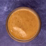Sriracha mayo in a glass bowl on a blue blackground.