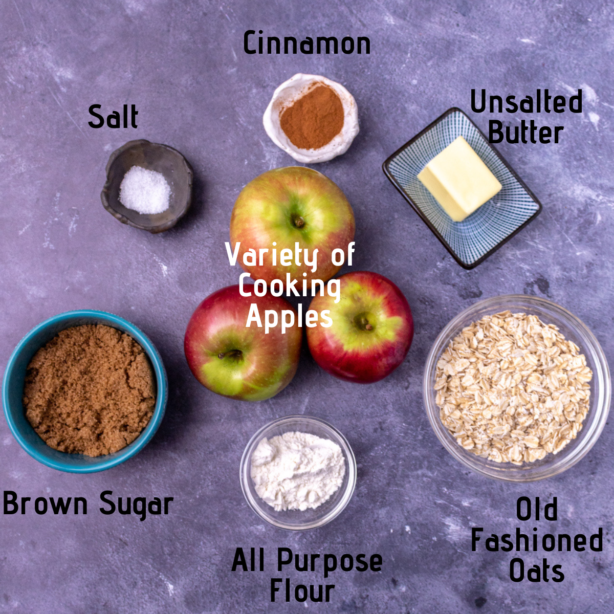 Raw ingredients laid out and labeled: Salt, ground cinnamon, unsalted butter, brown sugar, AP four, old fashioned oats and a variety of cooking apples.