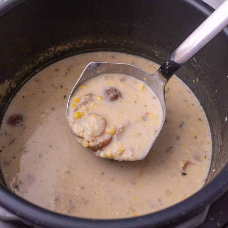 Corn chowder in the pressure cooker being ladled out with a ladle.