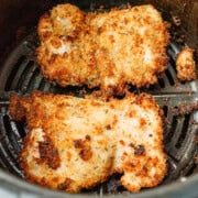 Two browned and breaded chicken thighs in the air fryer.